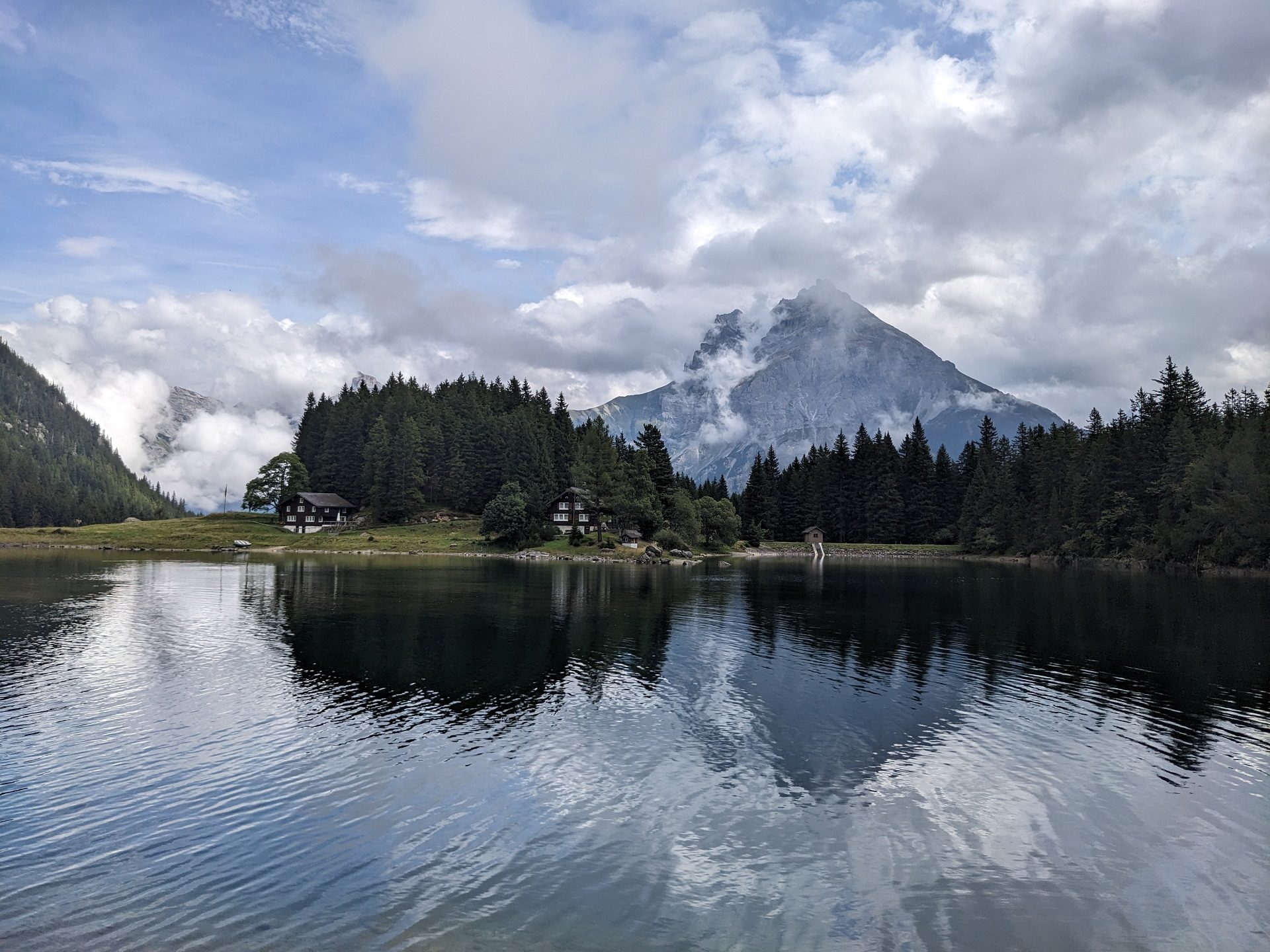 Person schwimmt bei Dämmerung in einem Bergsee mit Felswänden